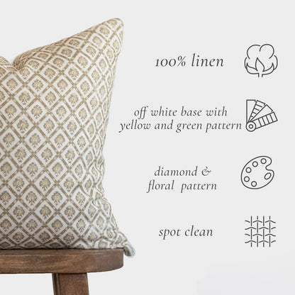 Cream linen lumbar pillow with tan diamond and floral pattern, displayed on wooden chair.