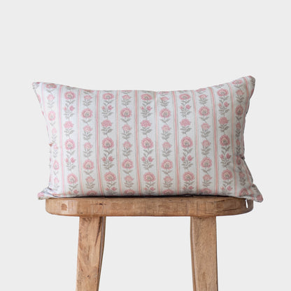 Rectangular pillow with pink floral pattern and vertical stripes on wooden bench.