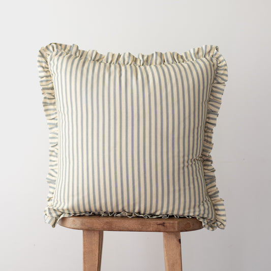 Square throw pillow with vertical stripe pattern and ruffled edges on all sides, displayed on wooden stool.