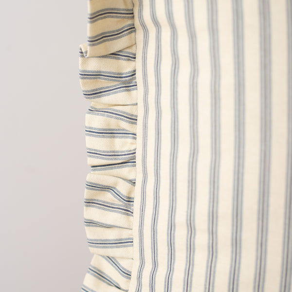 Cream pillow with navy horizontal stripes on left side and vertical stripes on right side with ruffled edge detail.