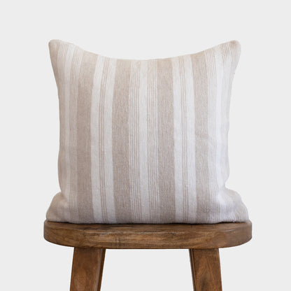 Tan and white striped pillow with vertical texture displayed on wooden chair seat.