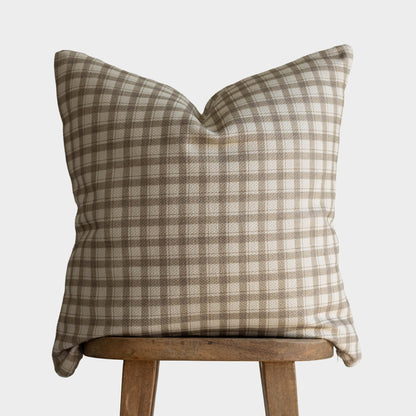 Tan and cream gingham patterned cotton pillow cover with thick weave displayed on wooden stool.
