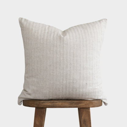 Cream textured pillow with vertical ribbed pattern resting on wooden stool.