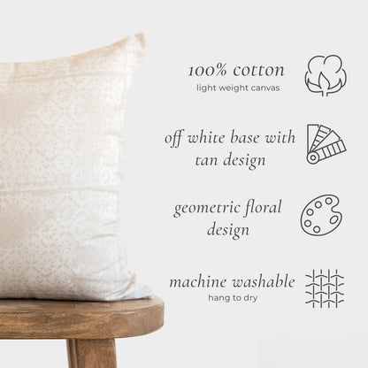 Cream cotton pillow with faded tan geometric floral pattern on off-white base, displayed on wooden stool.