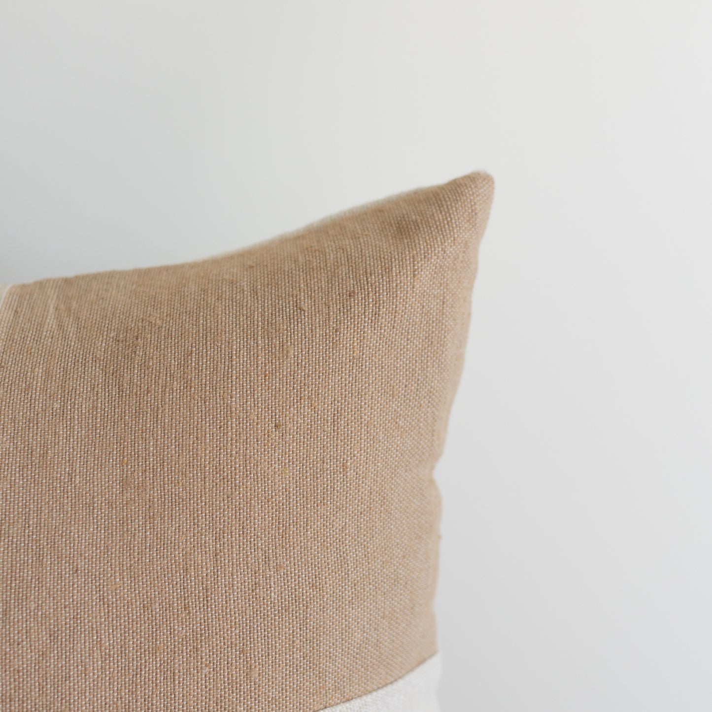 Tan textured pillow with a square shape and soft woven fabric surface.