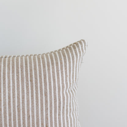 Tan and white striped lumbar pillow with vertical ribbed texture and white piping along the edge.