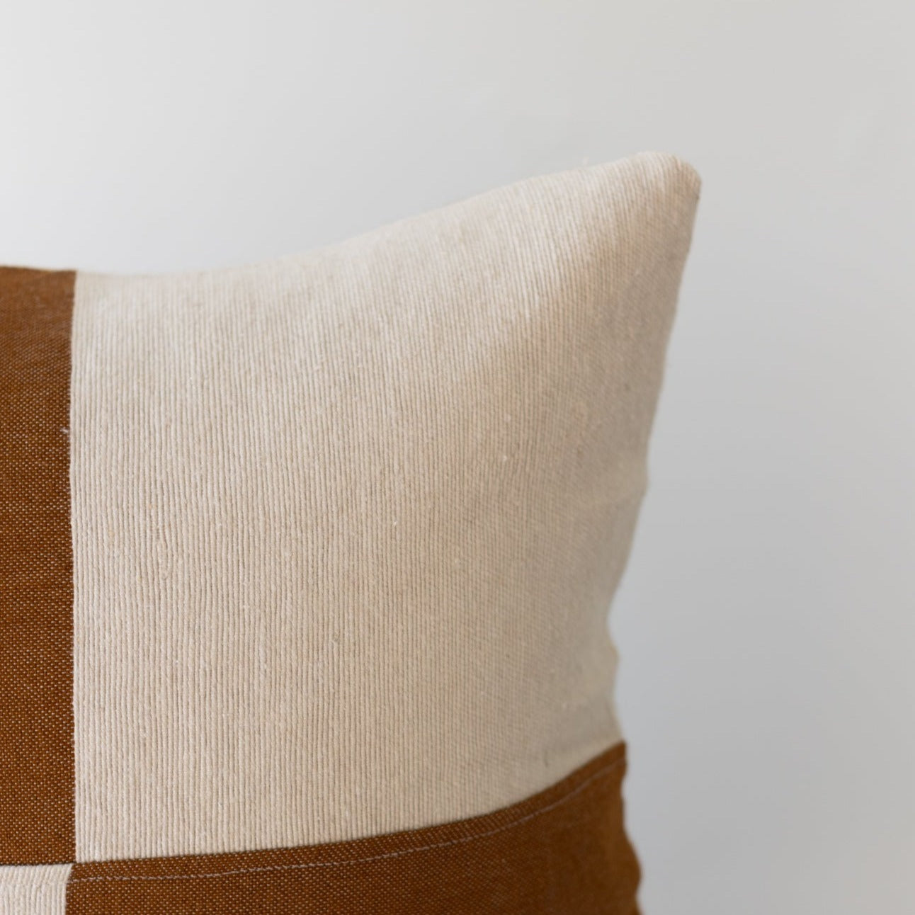 Cream and brown textured throw pillow with ribbed cream center and solid brown striped borders, 22 inches.