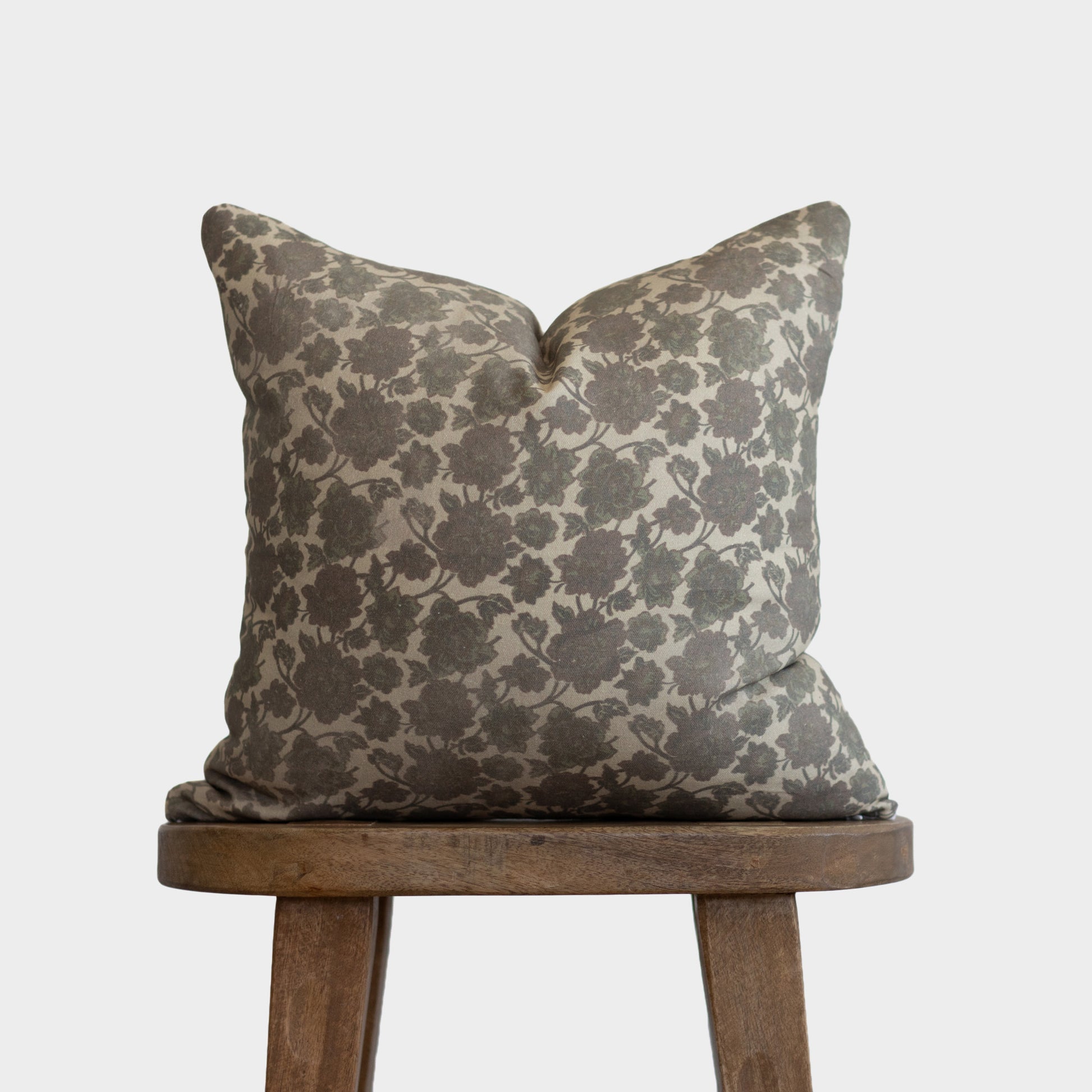 Nora pillow with gray and cream damask pattern on wooden stool.