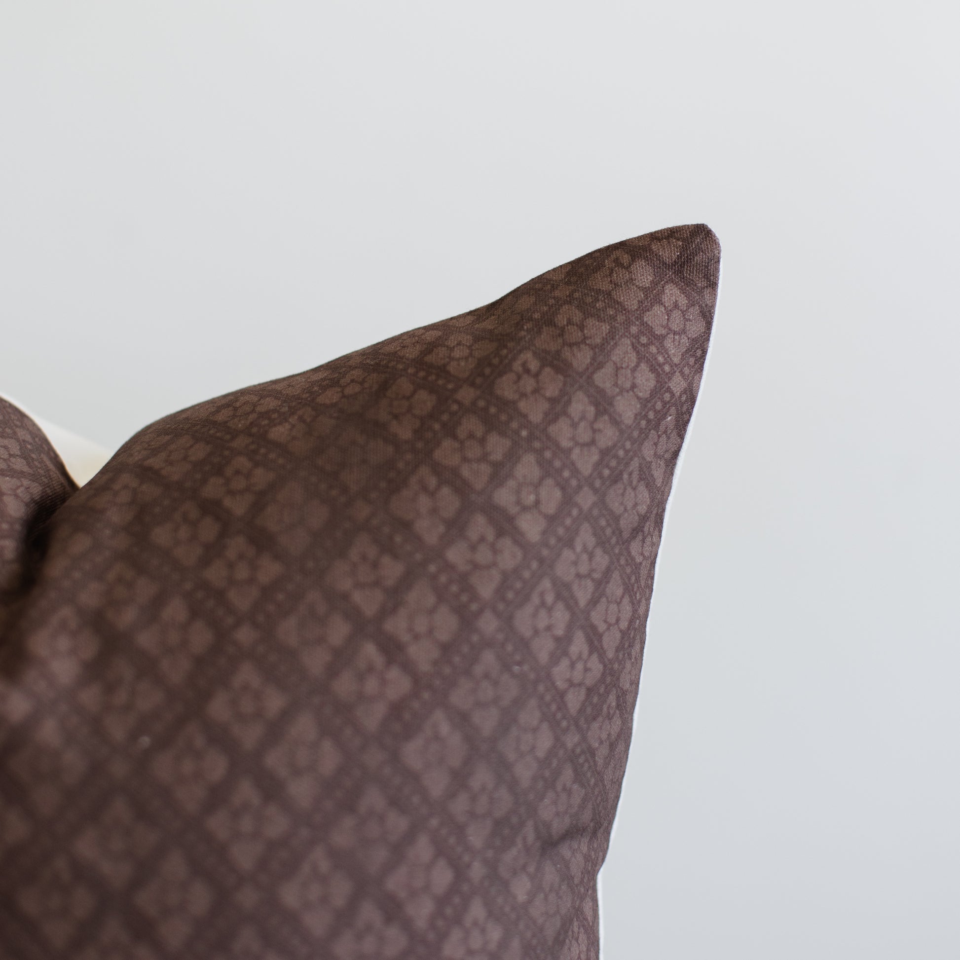 Maroon pillow with quilted geometric pattern and folded corner detail.