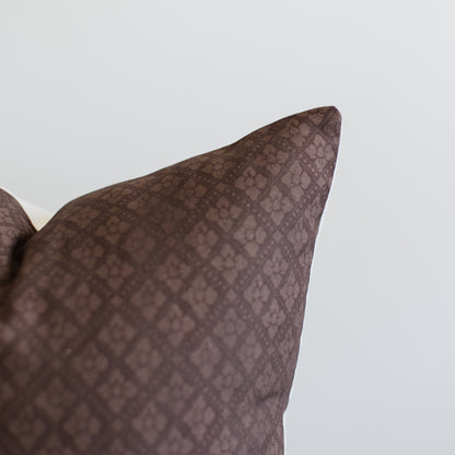 Maroon pillow with quilted geometric pattern and folded corner detail.