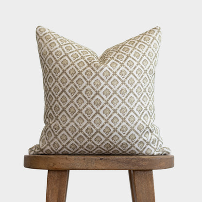 Cream linen pillow with tan geometric diamond and floral pattern, displayed on wooden stool.