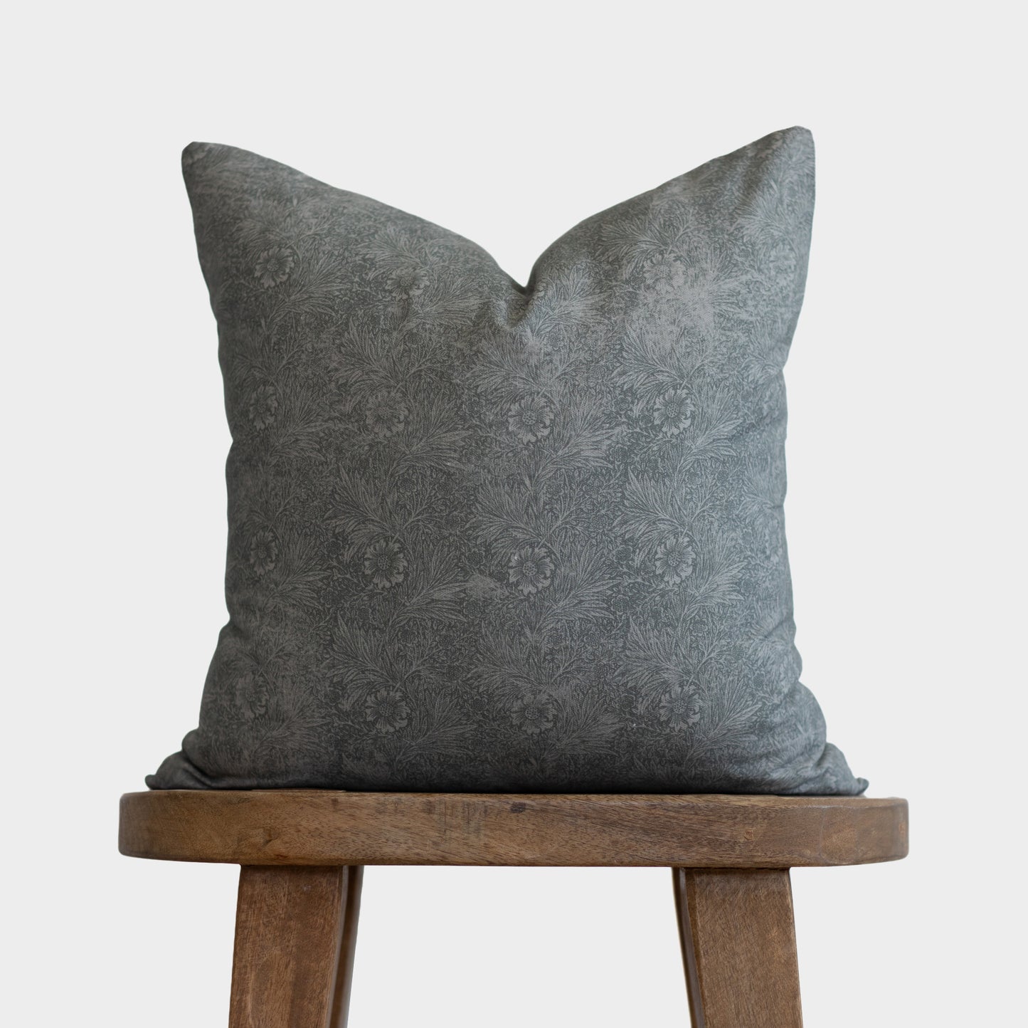 Gray damask patterned pillow with envelope closure displayed on wooden stool.