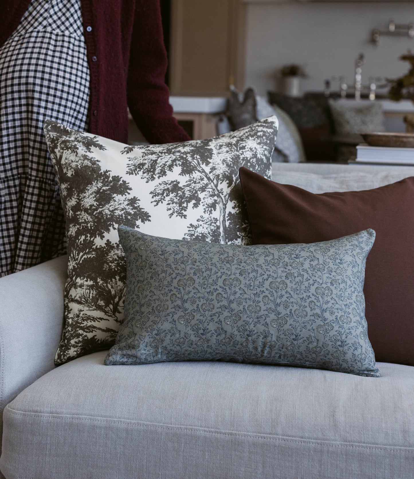 Blue-green patterned rectangular pillow displayed on a cream-colored sofa with coordinating decorative pillows.