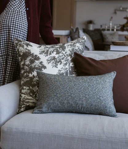 Blue-green patterned rectangular pillow displayed on a cream-colored sofa with coordinating decorative pillows.