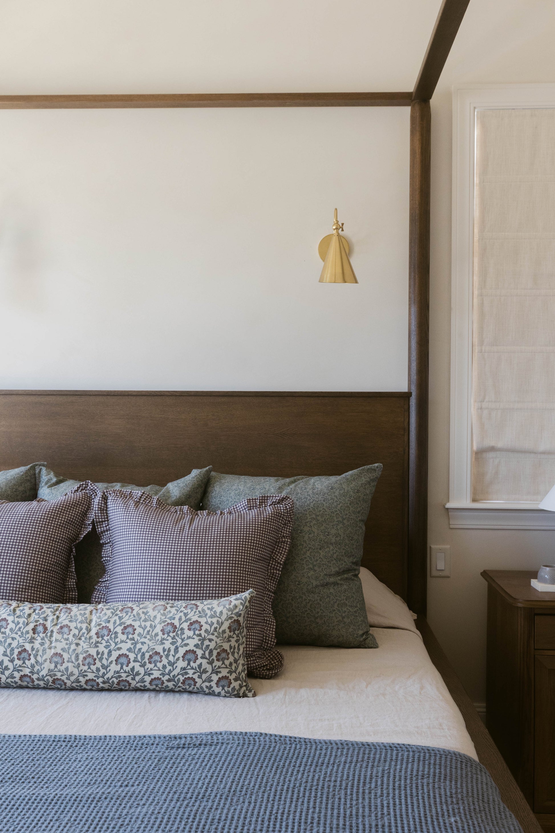 Plum and white mini gingham ruffle pillow with ruffled edge trim on bed with other textured pillows.
