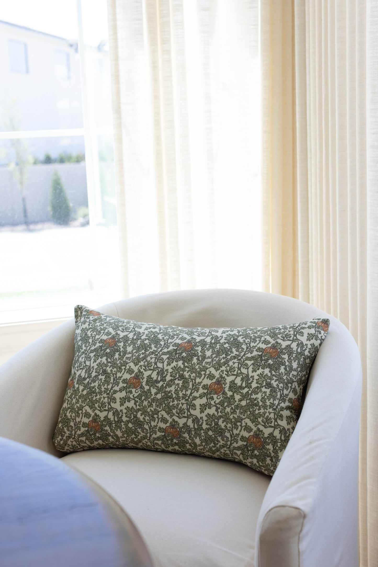 Rectangular pillow with green and cream botanical print featuring gourds and ivy vines with rust-colored accents.