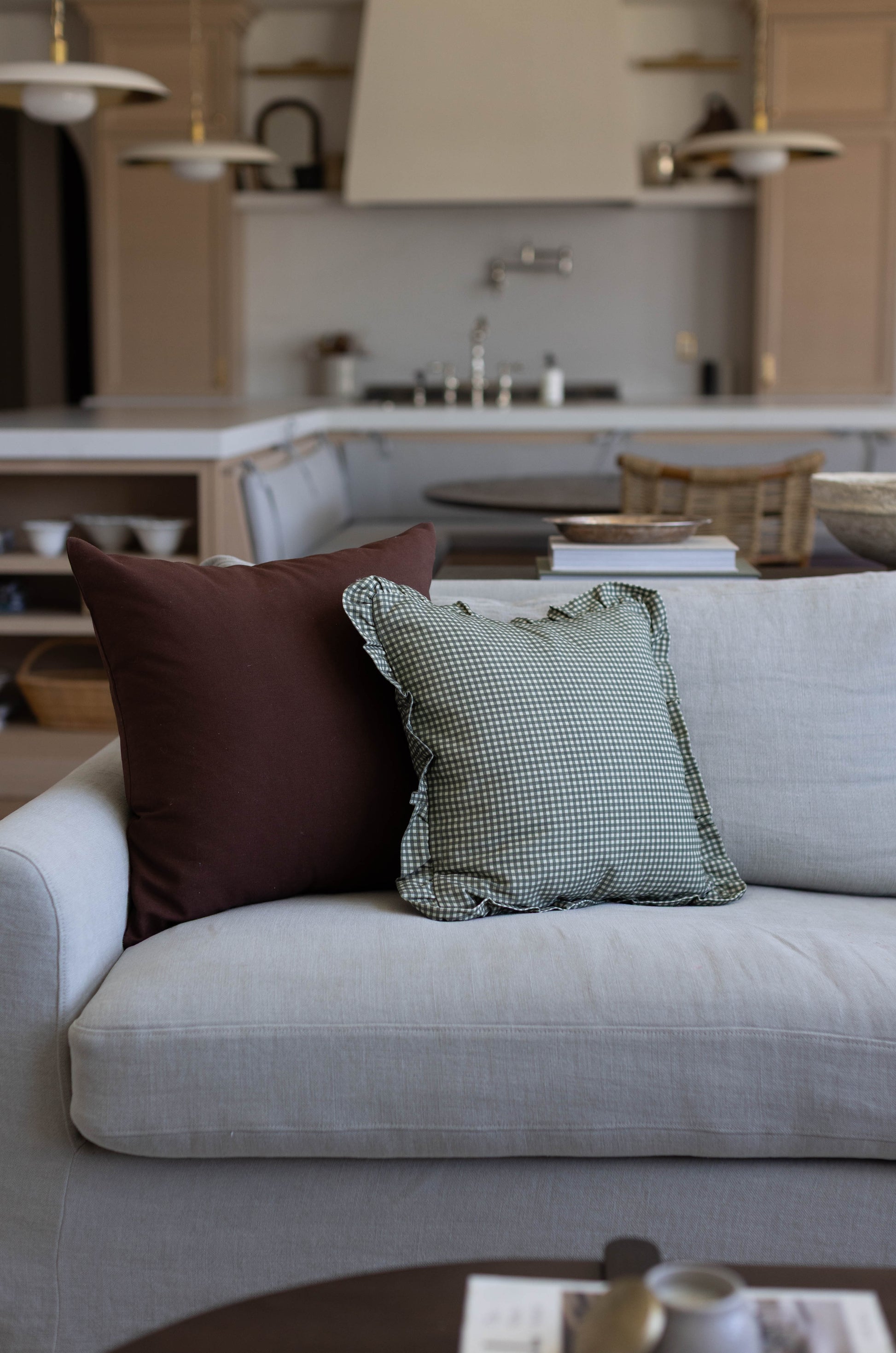 Light gray upholstered sofa with brown and green gingham patterned throw pillows in a modern living room.