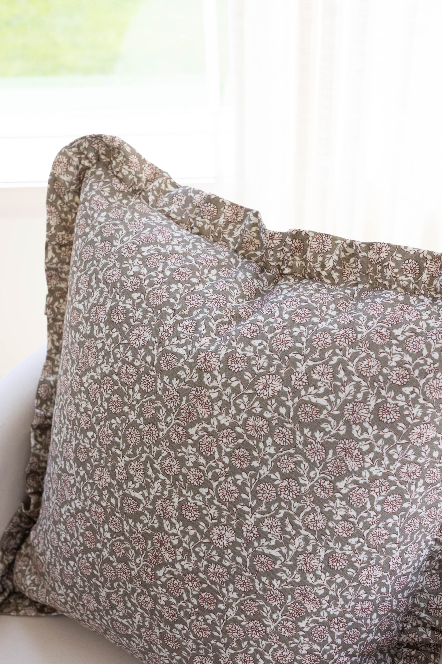 Taupe and white floral patterned pillow with ruffled edges.