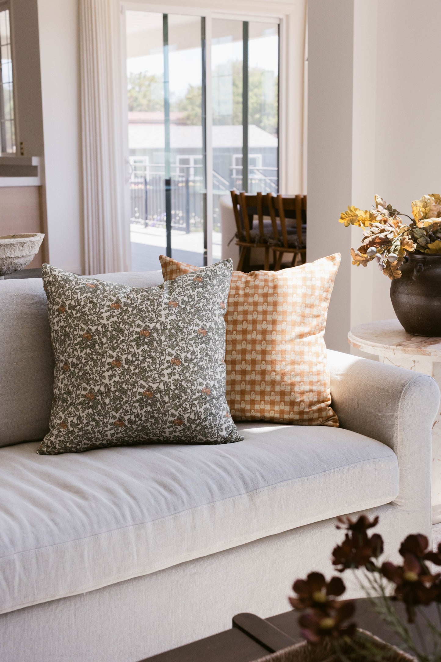 Peach and white gingham patterned throw pillow on a cream sofa.