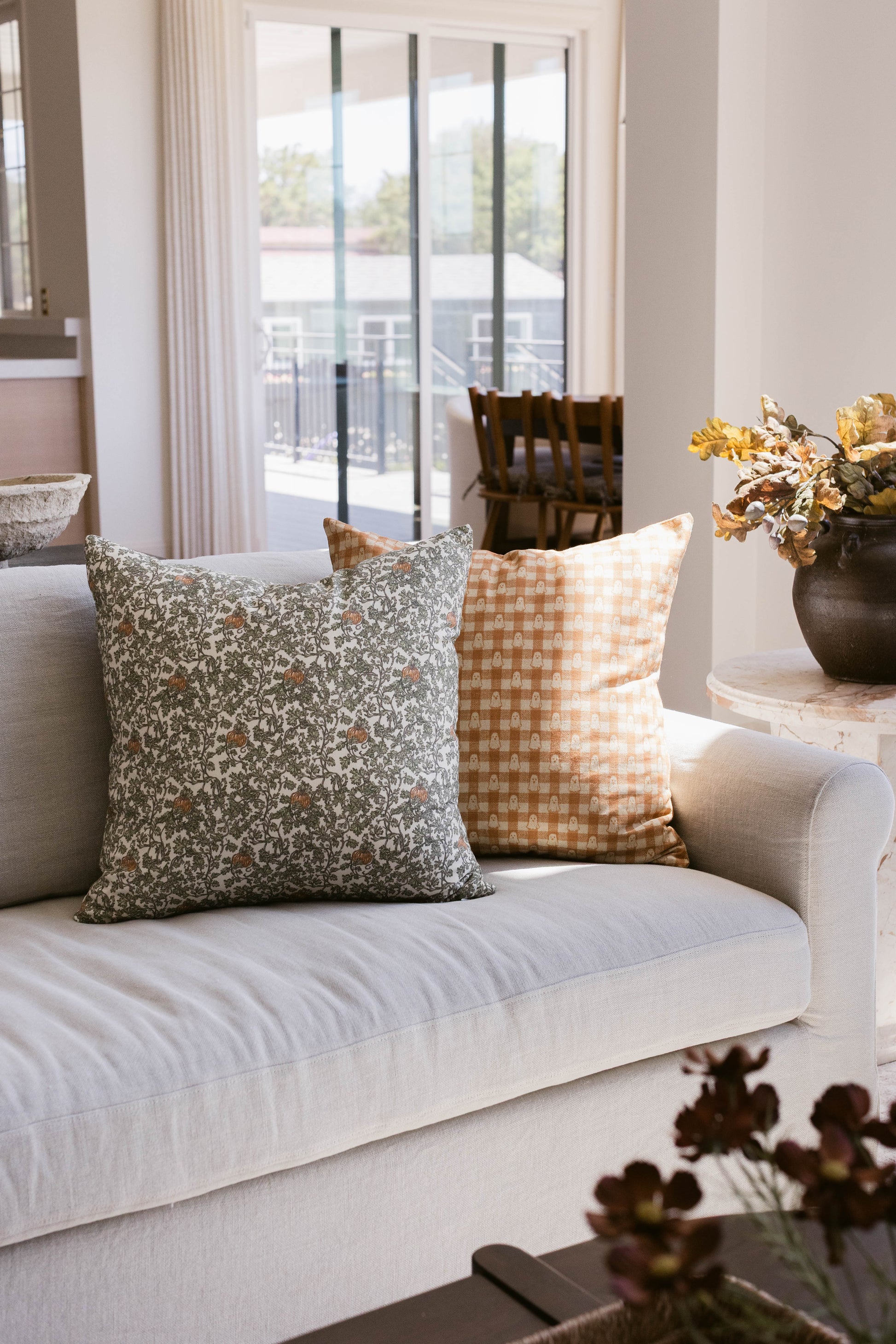 Peach and white gingham patterned throw pillow on a cream sofa.