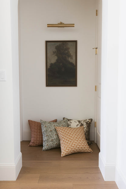 Four decorative throw pillows in varying patterns including gingham, floral, and solid designs arranged on a wooden floor.