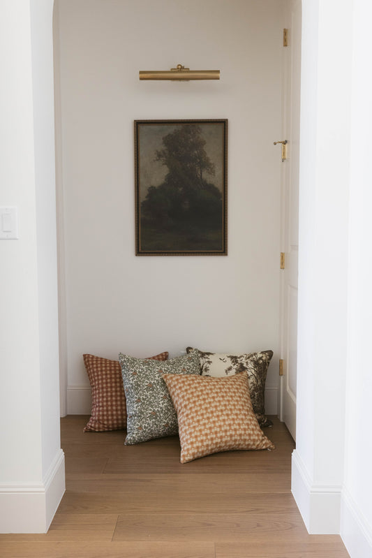 Four decorative throw pillows in varying patterns including gingham, floral, and solid designs arranged on a wooden floor.