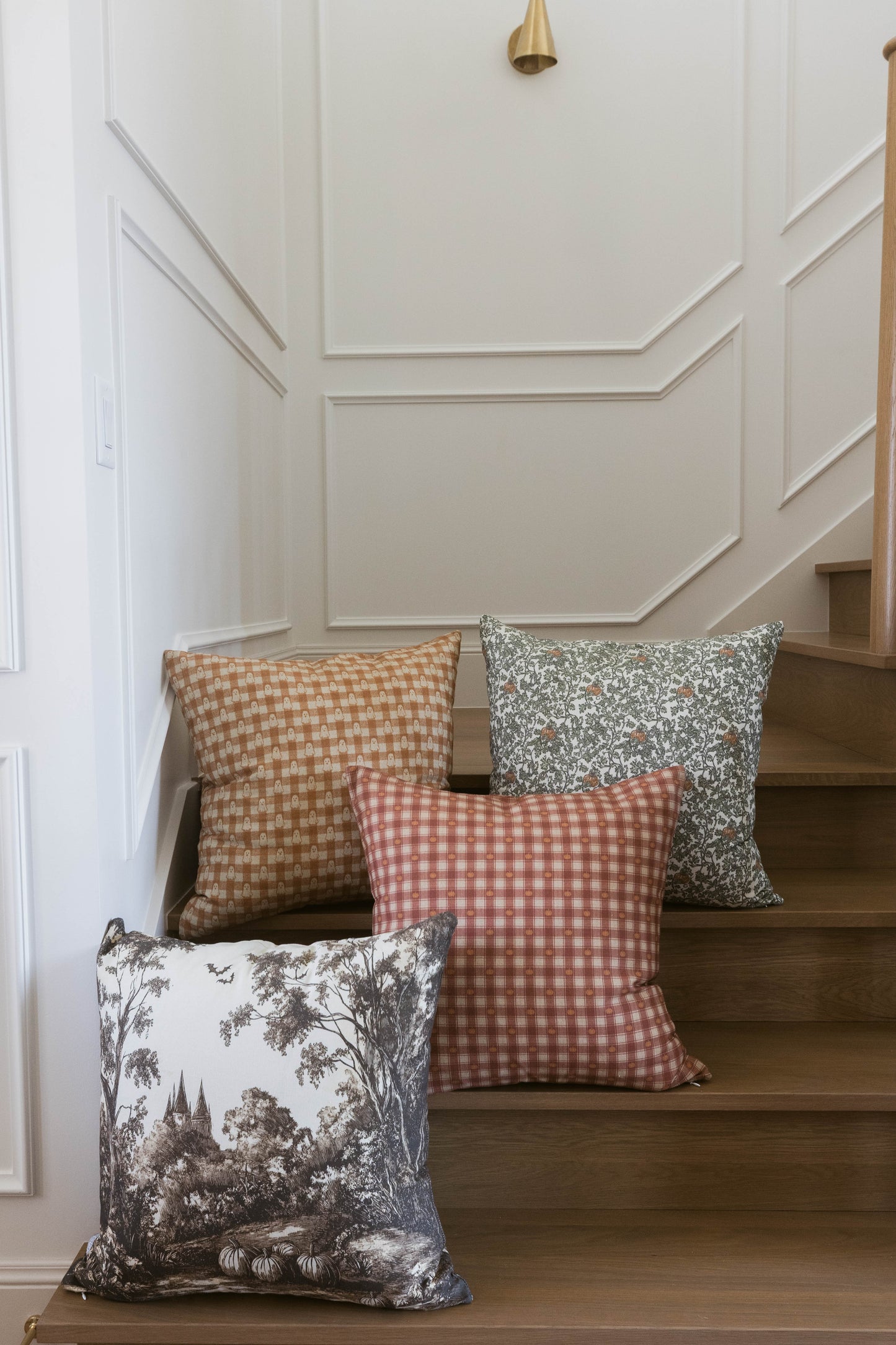 Red and white gingham pillow displayed on wooden stairs with coordinating patterned pillows.