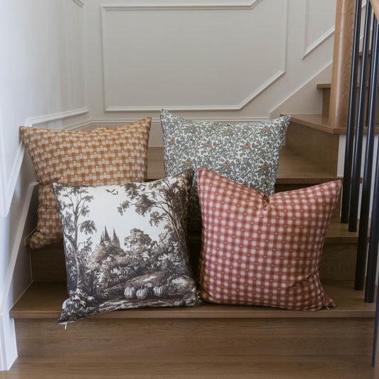 Orange and white checkered plaid pillow displayed on wooden bench with coordinating decorative pillows.