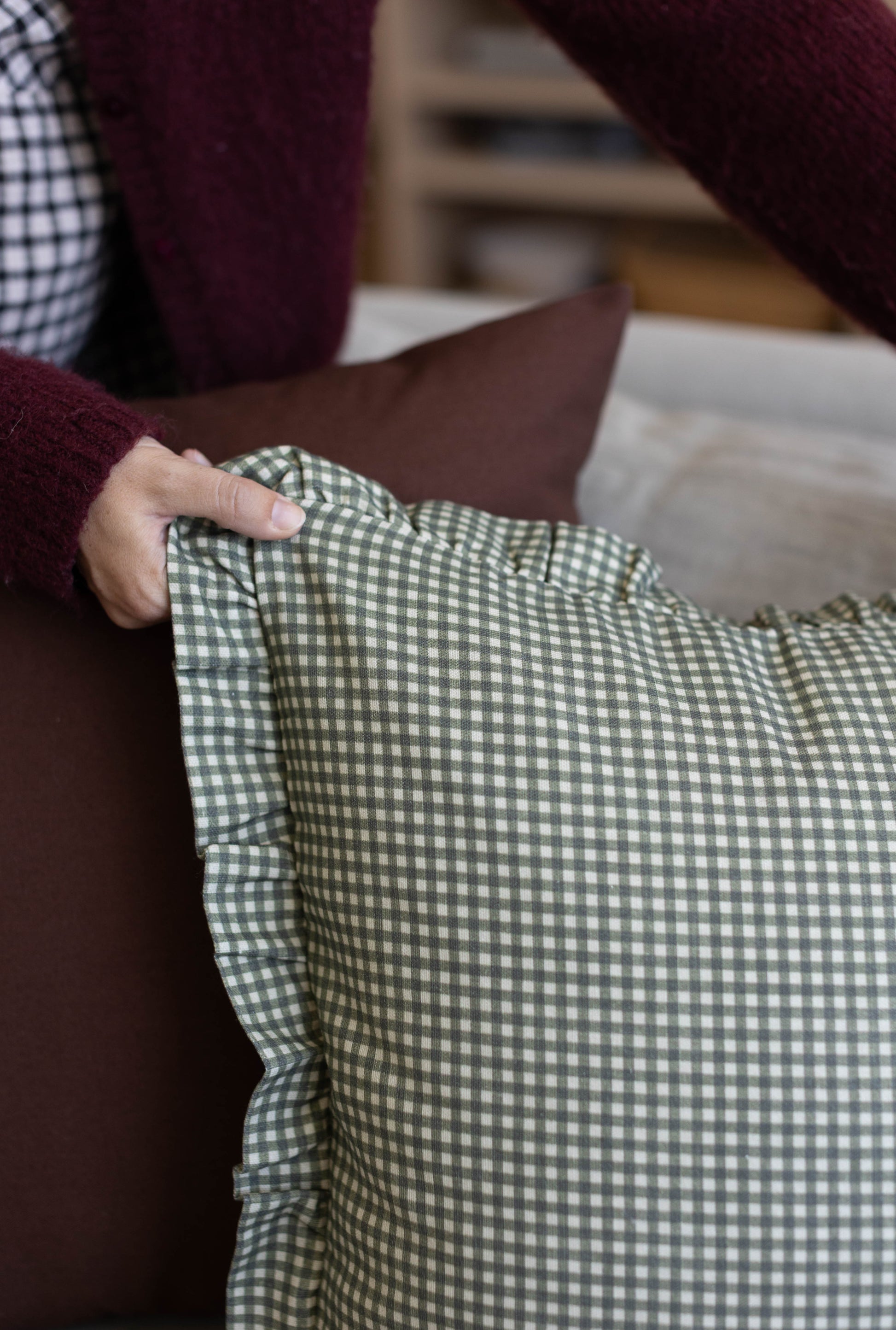Green and white gingham cloth with ruffled edge held in hand.