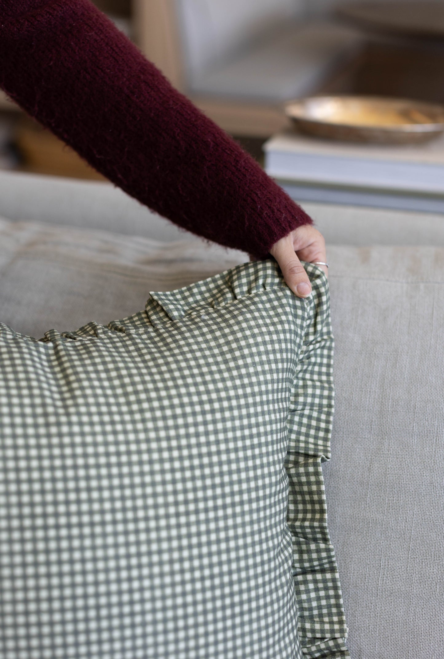 Green and white gingham checkered fabric with ruffled edge detail held in hand.