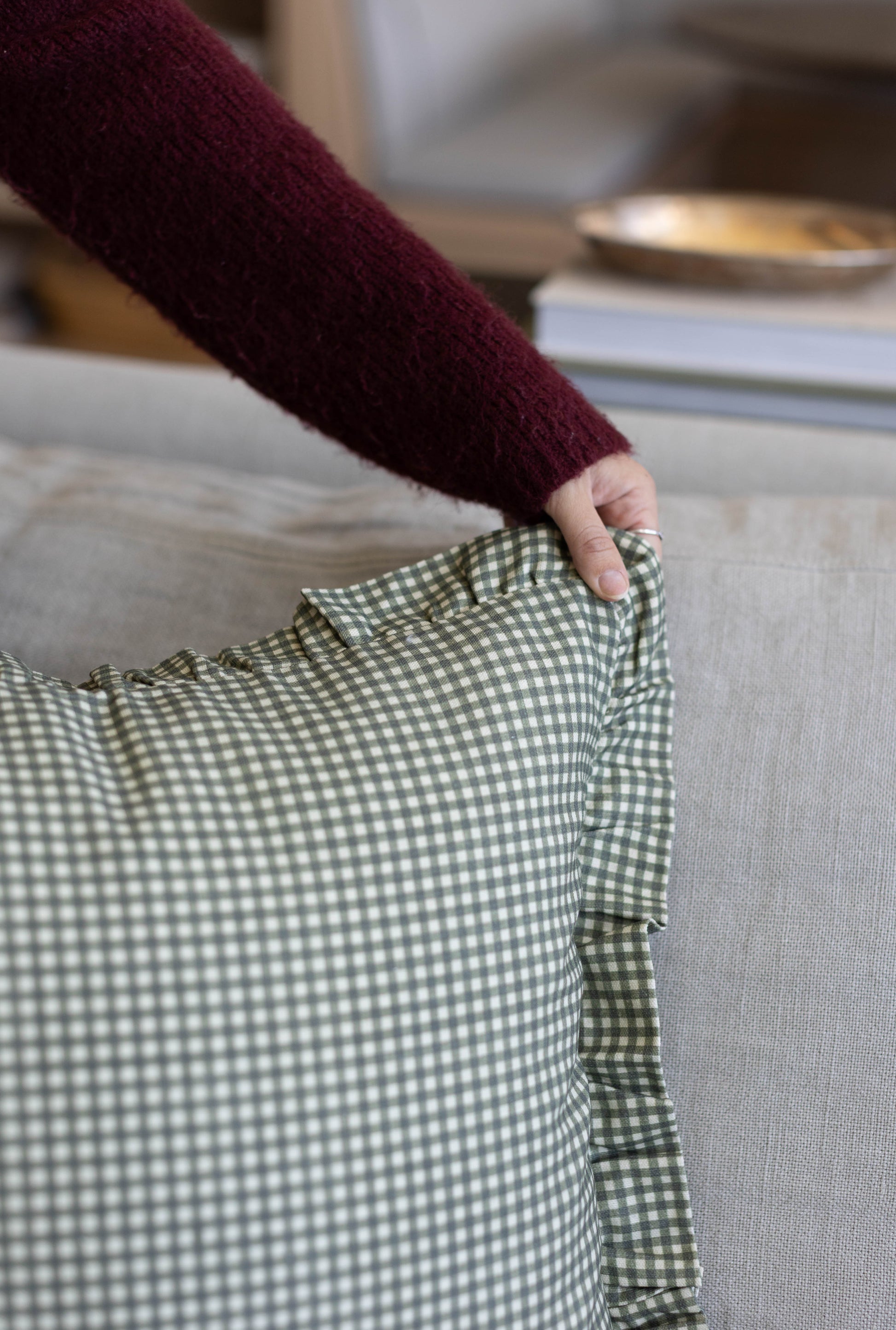 Green and white gingham checkered fabric with ruffled edge detail held in hand.
