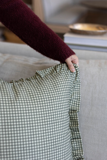 Green and white gingham checkered fabric with ruffled edge detail held in hand.