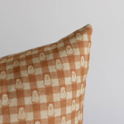 Terracotta and cream gingham pillow with small ghost motifs in a checked pattern.