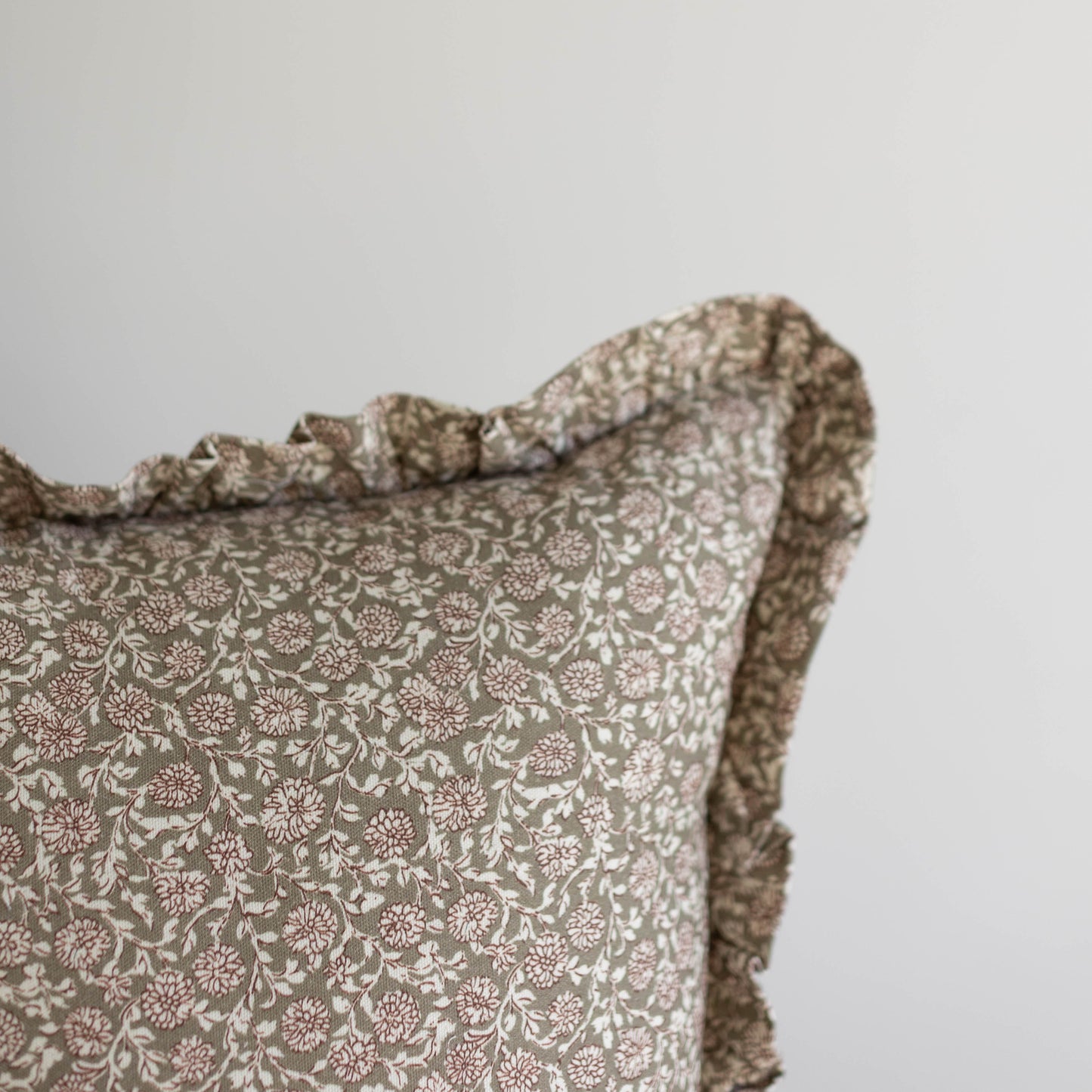Beige cushion cover with small floral pattern and ruffled edge trim.