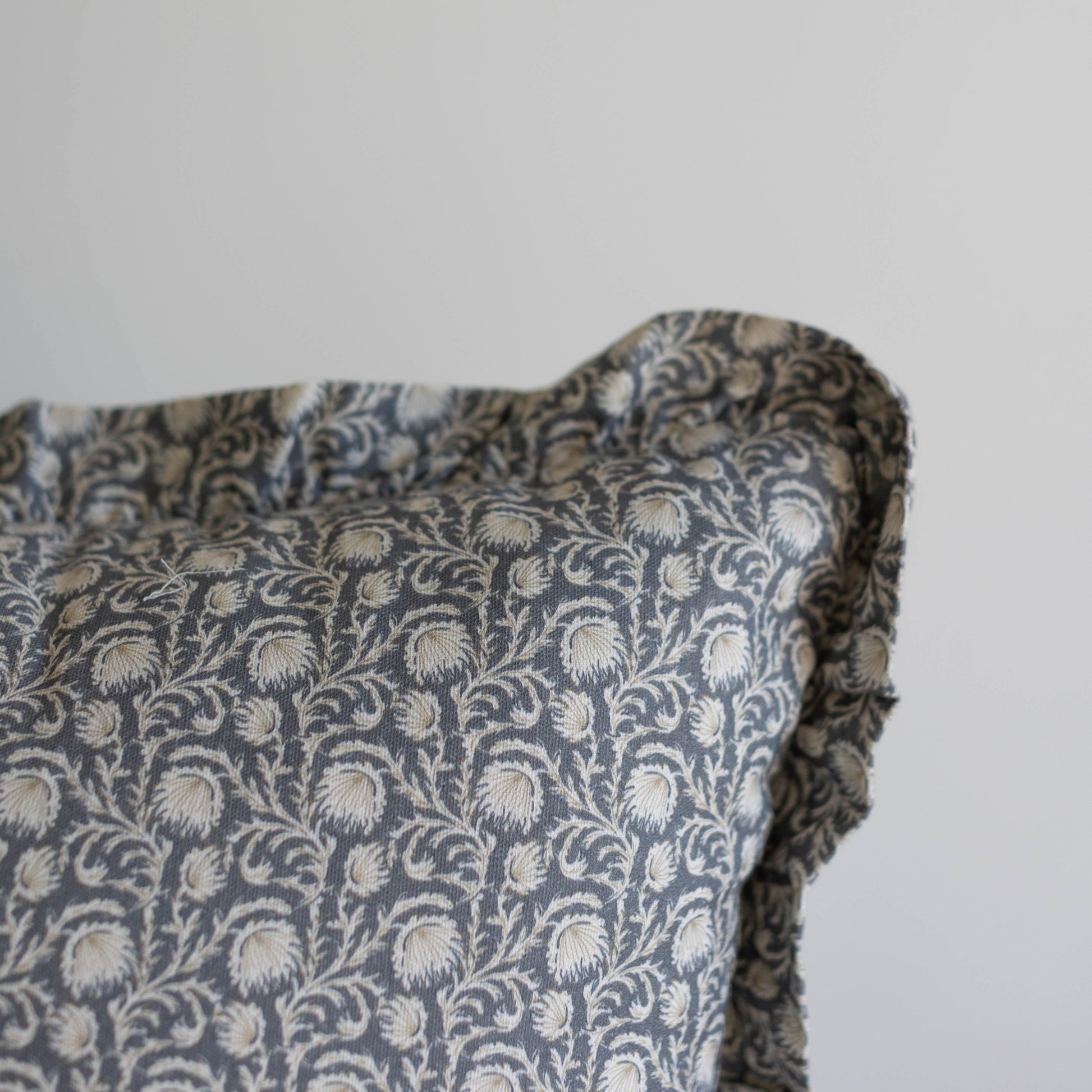 Blue and cream damask patterned pillow with ruffled edges and scrolling floral design.
