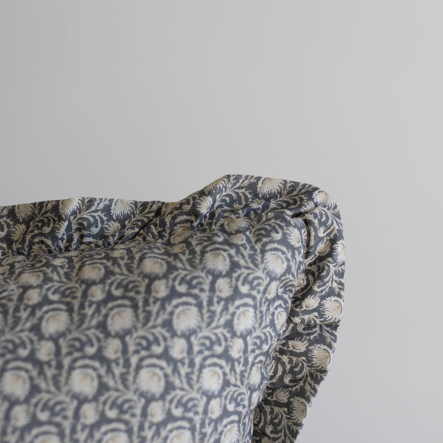 Decorative pillow with blue and cream damask pattern and ruffled edge trim.