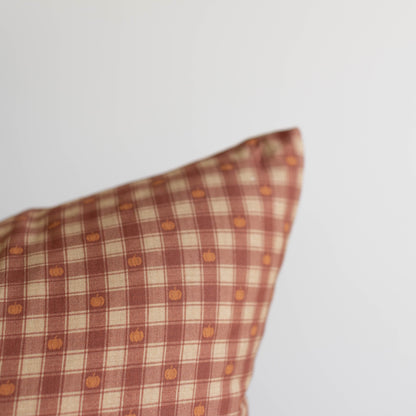 Red and cream plaid pillow with small orange pumpkin print throughout the pattern.