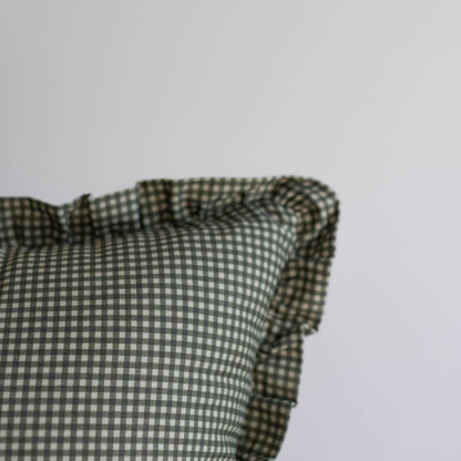 Green and white mini gingham pillow with ruffled edges on gray background.