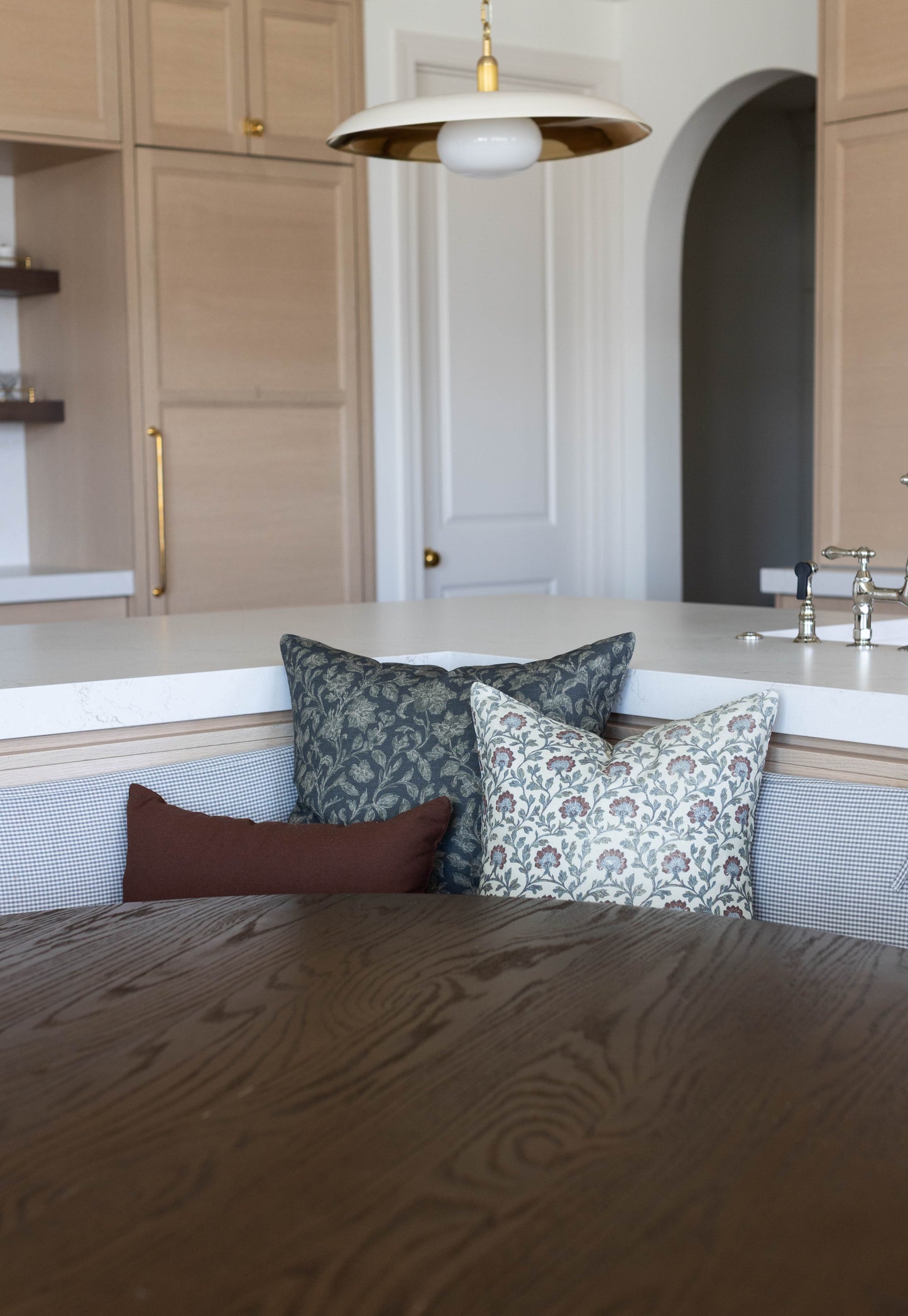 Three decorative pillows in varying patterns displayed on a kitchen island seating area.