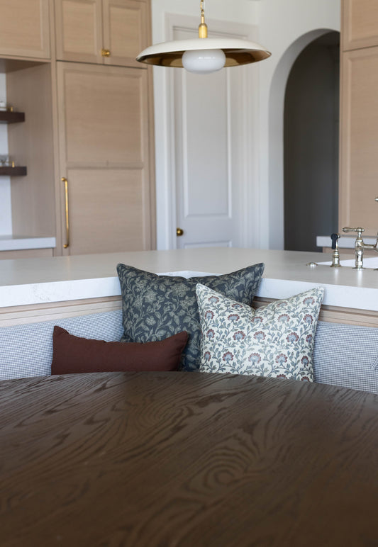 Three decorative pillows in varying patterns displayed on a kitchen island seating area.