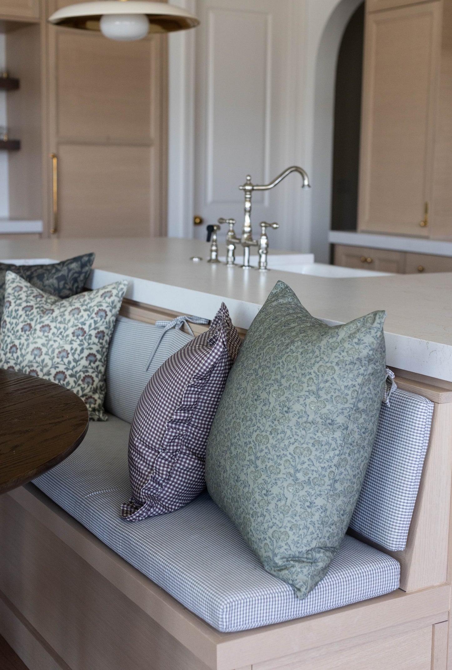 Green and plum patterned pillows with ruffle edges arranged on bathroom counter.
