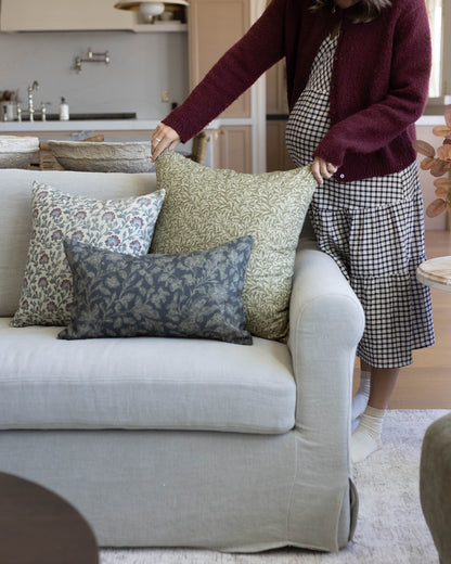 Green patterned throw pillow displayed on cream upholstered sofa with coordinating decorative pillows.