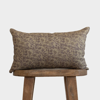 Rectangular pillow with taupe botanical print pattern on wooden stool.