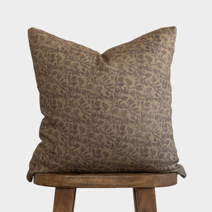 Faye pillow with tan and brown leaf pattern displayed on wooden stool.