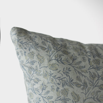 Blue and gray botanical patterned pillow with leaf motif on neutral background.