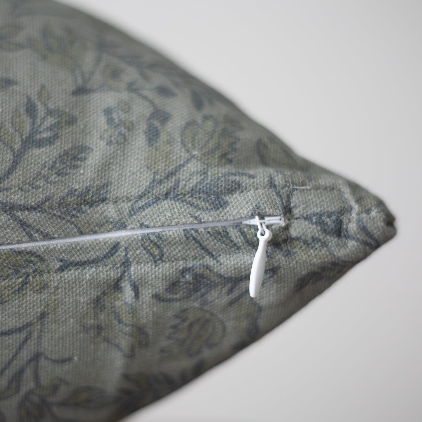 Blue patterned pillow with white zippered closure on side.
