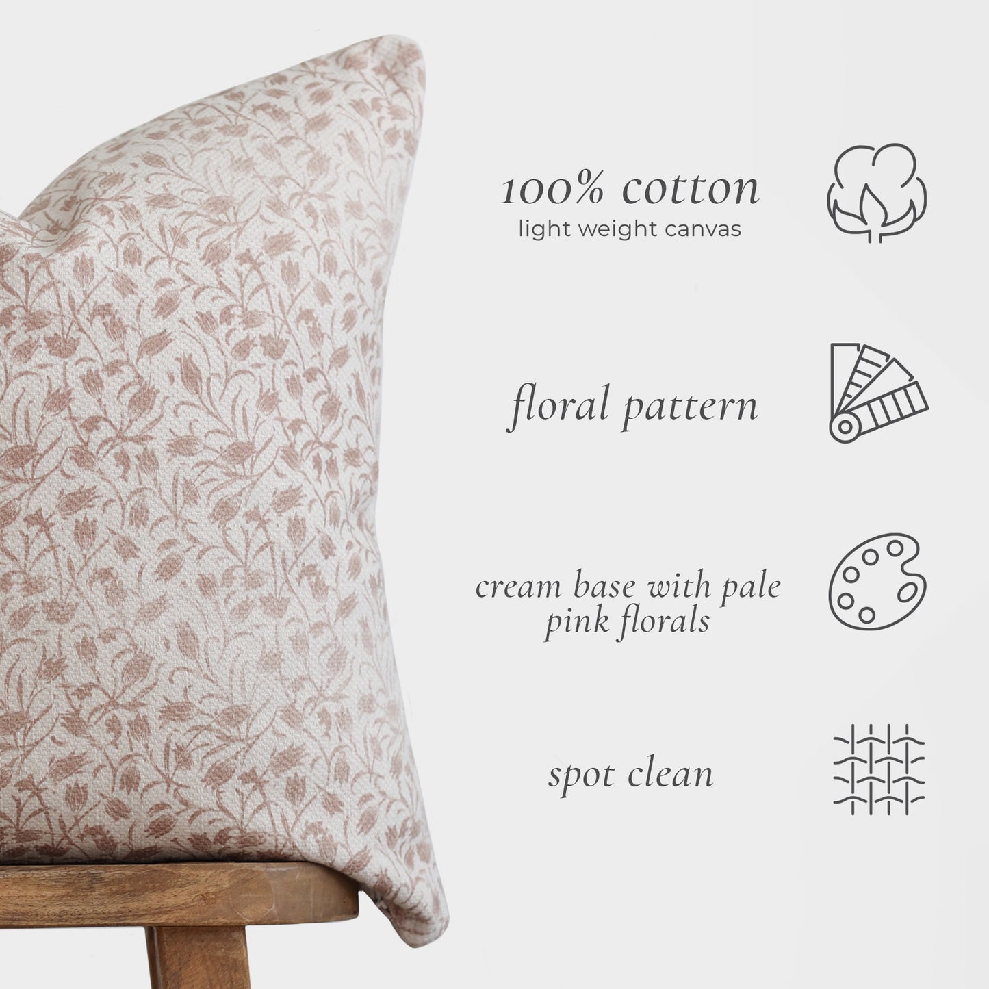Cream cotton pillow with pale pink floral pattern on wooden chair.