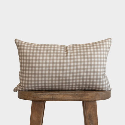 Tan and white gingham patterned lumbar pillow on wooden stool.