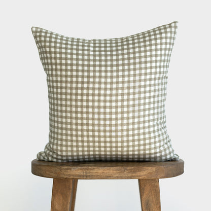 Sage green and white gingham check pillow displayed on a wooden stool.