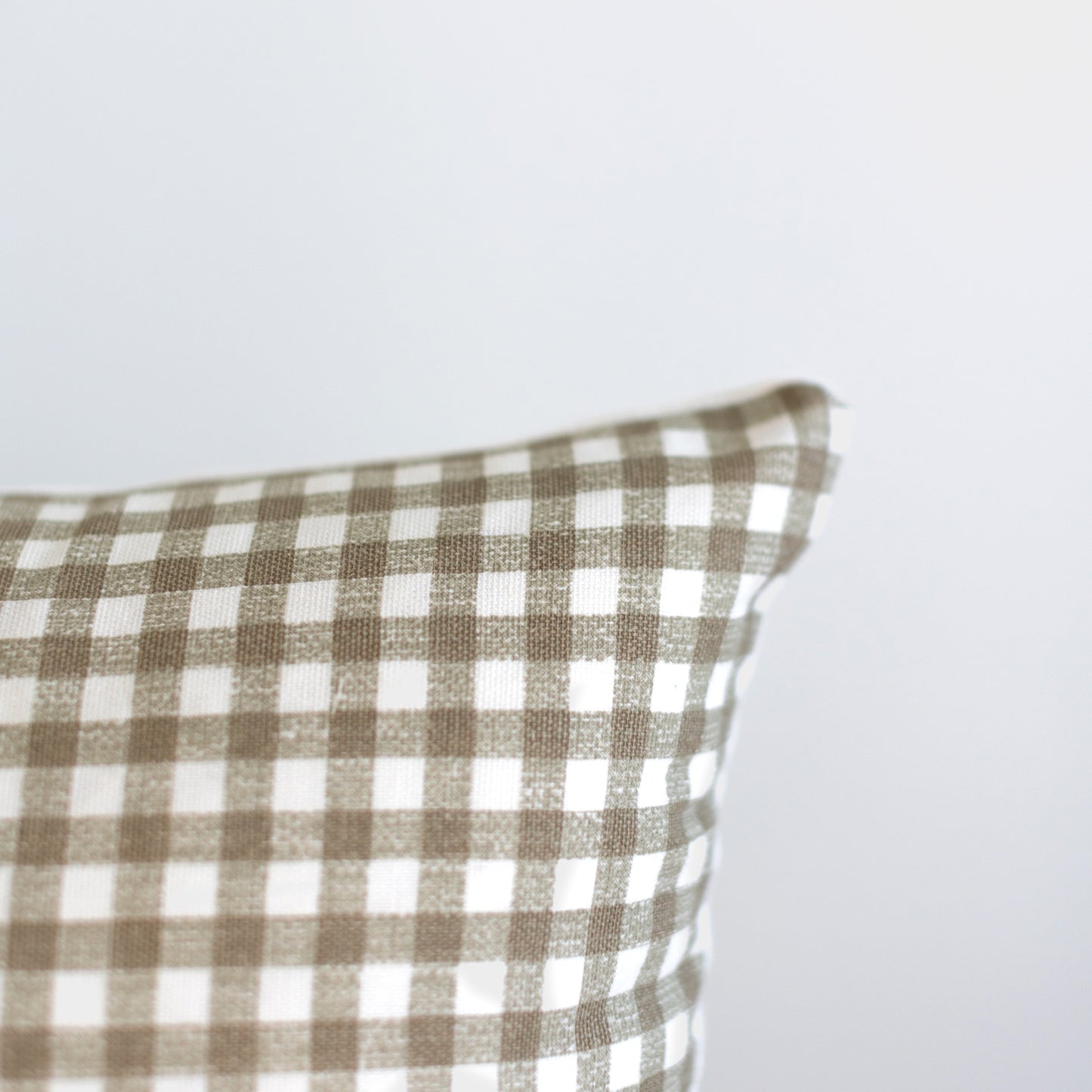 Tan and white gingham patterned pillow with checkered weave fabric.